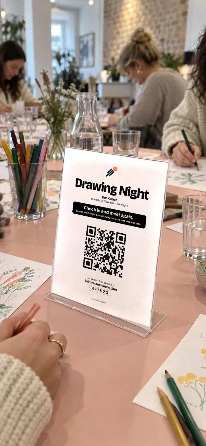 View through a phone camera at the card of a drawing night with the QR code: Drawing Night. Check in and meet again.
