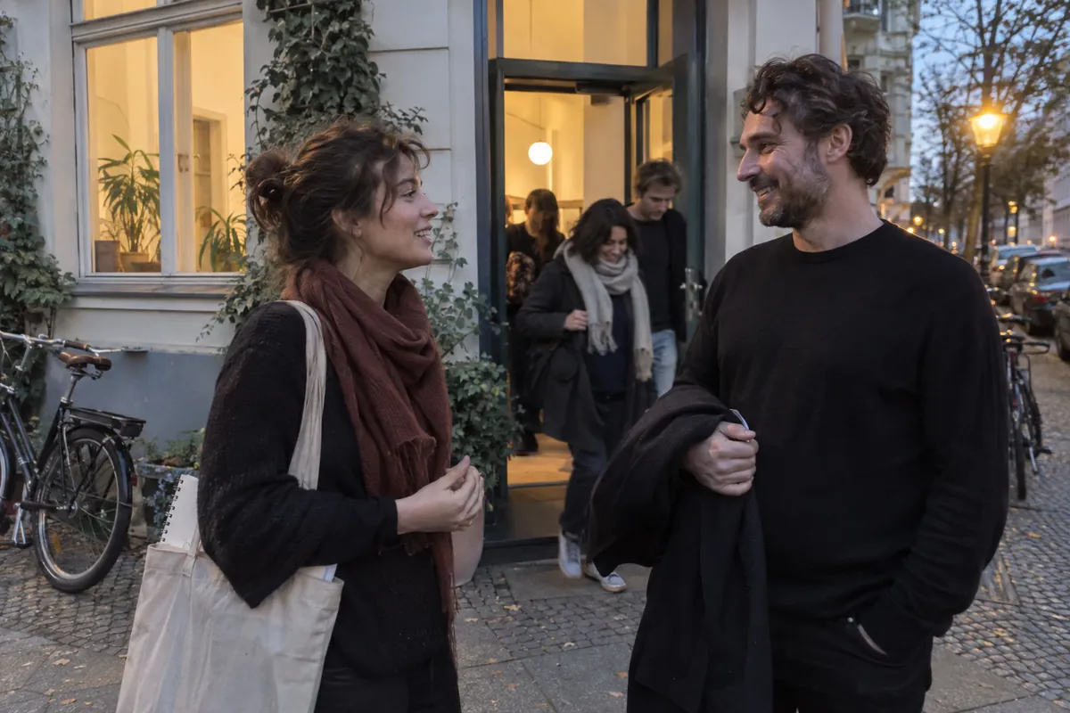 Two people talking on the pavement outside a course room in a Berlin street at dusk