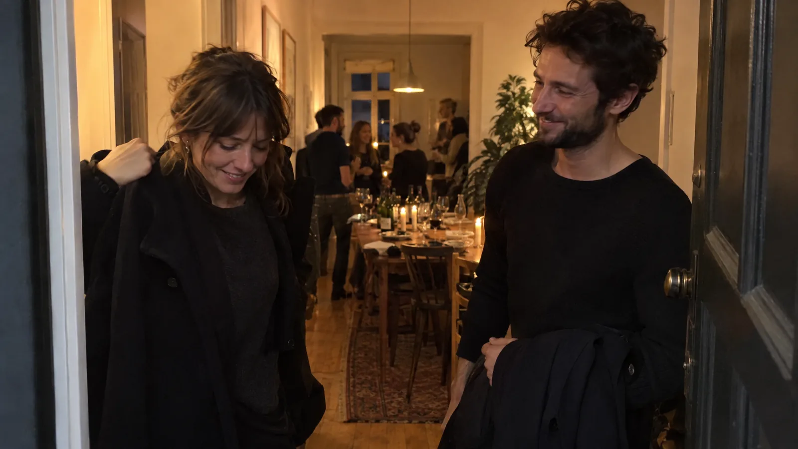 Two guests smiling as they say goodbye at the door at the end of a supper club, the candlelit table behind them